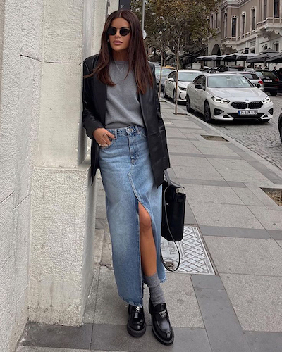 a model wearing a blazer and denim skirt outfit on the street