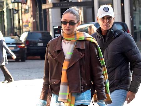 a gigi hadid paparazzi photo of her wearing a cropped jacket, scarf, and sunglasses