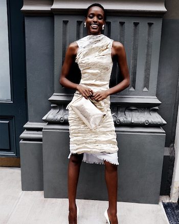 a model wearing a silver metallic dress holding a silver metallic purse